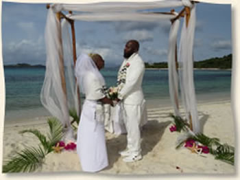 Bride and groom exchange vows under bamboo arch at Lindquist Beach.